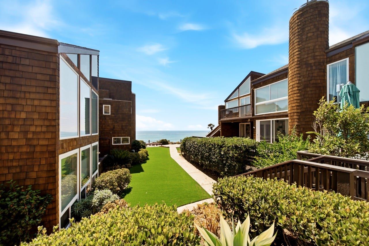 A strip of lawn and path running between two buildings to the ocean at the far end