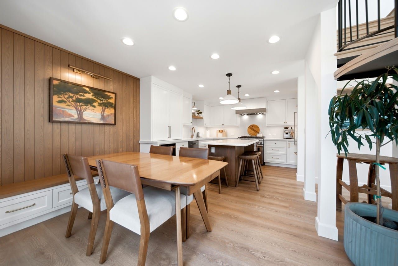 The dining table against a panelled oak wall, open to the kitchen