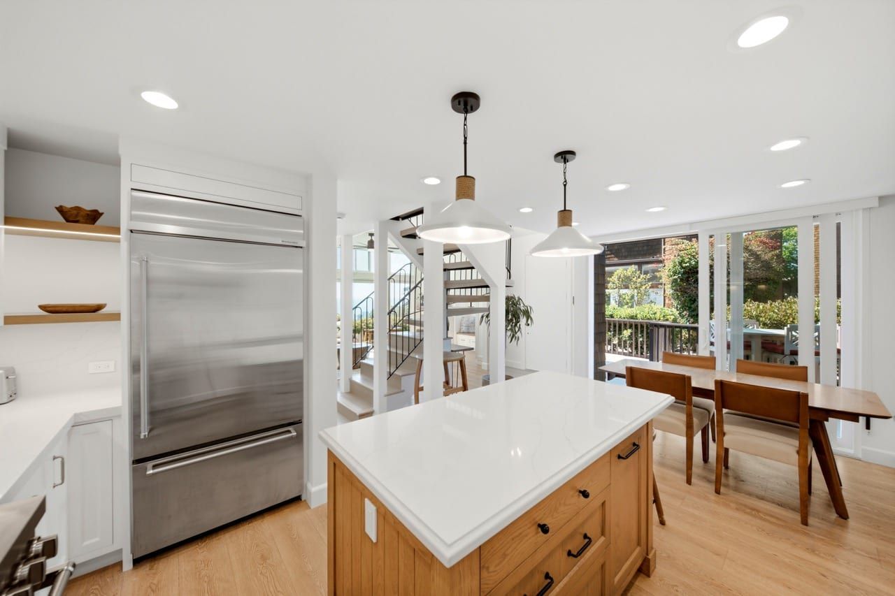 The kitchen island and built-in refrigerator, with the dining area beyond